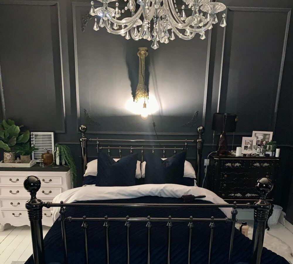Metal bed frame in a dark bedroom with chandelier light
